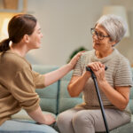 Elderly patient and caregiver spending time together. Senior woman holding cane.