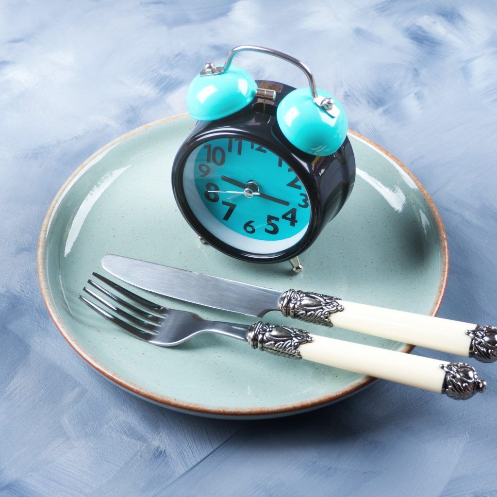 Intermittent fasting concept with blue alarm clock